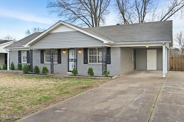 single story home with brick siding, concrete driveway, a front yard, fence, and an attached carport