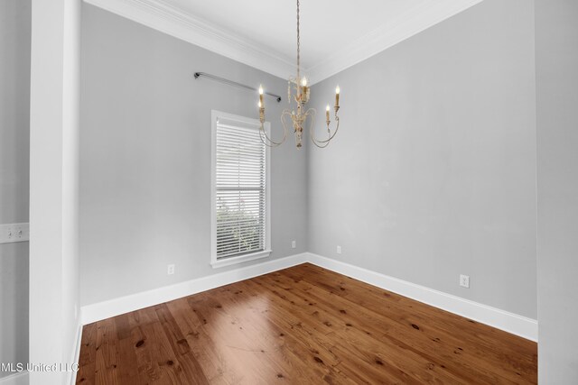 spare room with crown molding, baseboards, a notable chandelier, and wood finished floors
