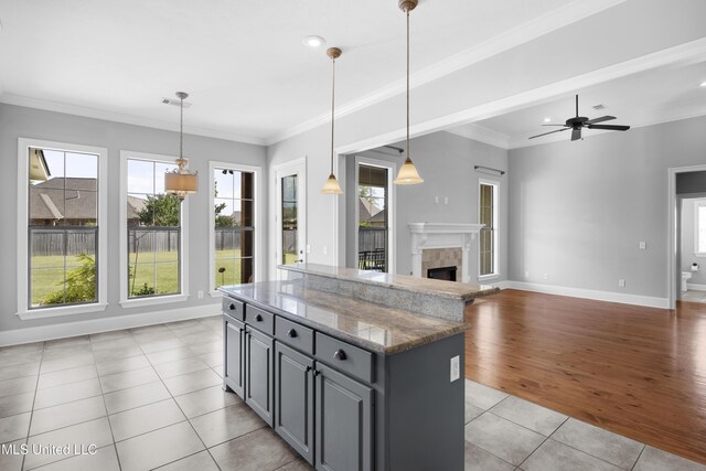kitchen featuring light tile patterned floors, gray cabinets, a healthy amount of sunlight, and a center island