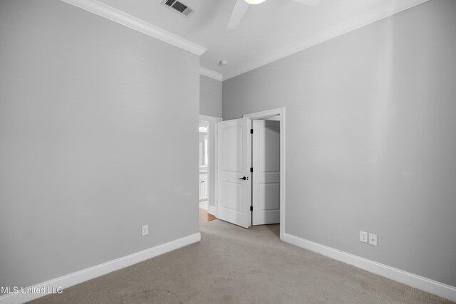 spare room featuring carpet flooring, a ceiling fan, baseboards, visible vents, and ornamental molding