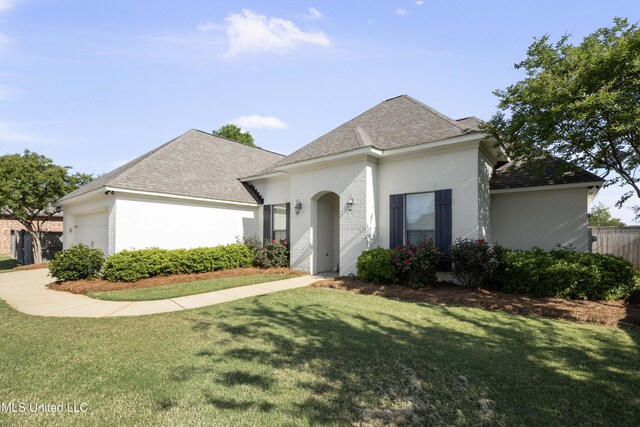 view of front of home featuring a shingled roof, an attached garage, and a front lawn