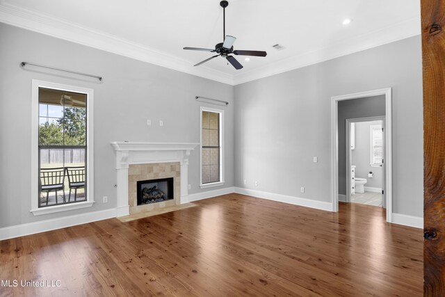 unfurnished living room with ceiling fan, crown molding, a fireplace, wood finished floors, and baseboards