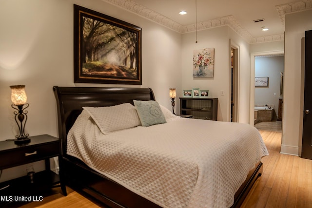 bedroom featuring visible vents, baseboards, ensuite bath, wood-type flooring, and recessed lighting