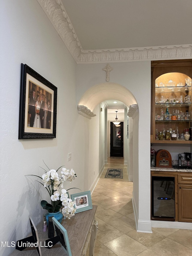 corridor with arched walkways, beverage cooler, and baseboards