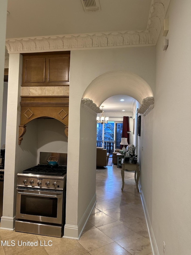 corridor featuring arched walkways, a chandelier, visible vents, and baseboards