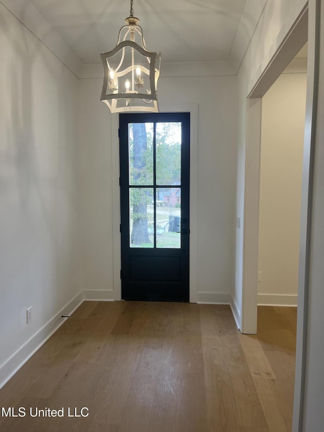 doorway with crown molding, light hardwood / wood-style flooring, and a chandelier