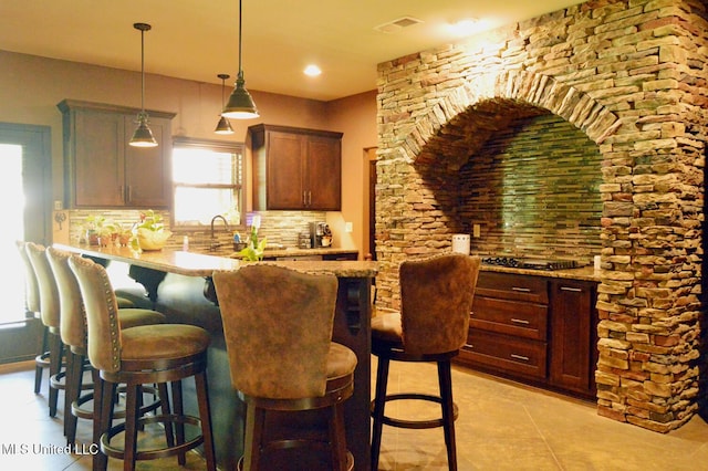 1088 S Red Banks Rd, Byhalia, MS 38611 - kitchen with decorative backsplash, a kitchen bar, hanging light fixtures, and light stone countertops