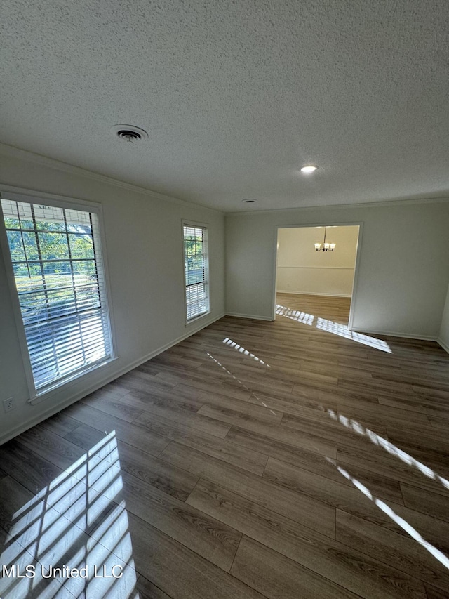 unfurnished room with dark wood-type flooring, a textured ceiling, and an inviting chandelier