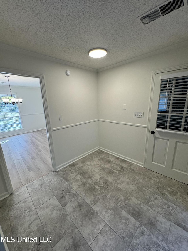 empty room featuring wood-type flooring, a textured ceiling, and an inviting chandelier