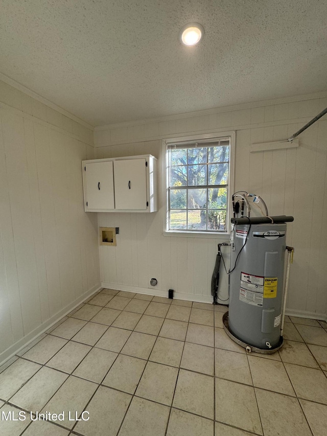 laundry area featuring light tile patterned flooring, electric water heater, a textured ceiling, and cabinets