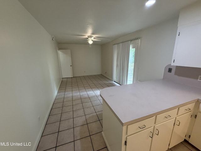 1632 Winchester St, Jackson, MS 39211 - kitchen featuring a ceiling fan, a peninsula, light countertops, light tile patterned flooring, and white cabinets