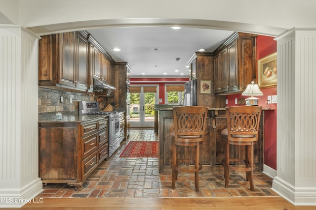 2629 Park View Dr, Biloxi, MS 39531 - indoor dry bar with stainless steel range with gas cooktop, under cabinet range hood, arched walkways, brick flooring, and french doors