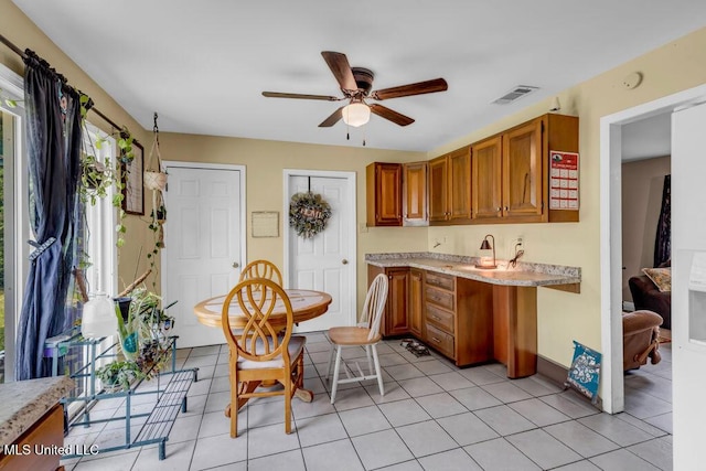 615 Baker St, Wiggins, MS 39577 - kitchen with a ceiling fan, brown cabinetry, light tile patterned floors, and baseboards