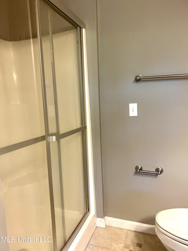 bathroom featuring baseboards, a stall shower, and toilet