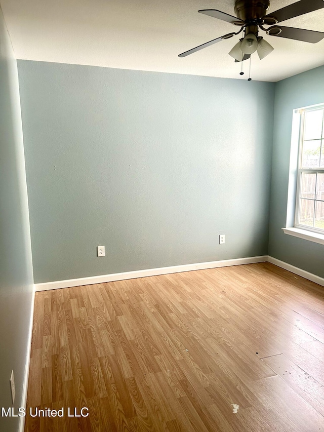 empty room with wood finished floors, a ceiling fan, and baseboards
