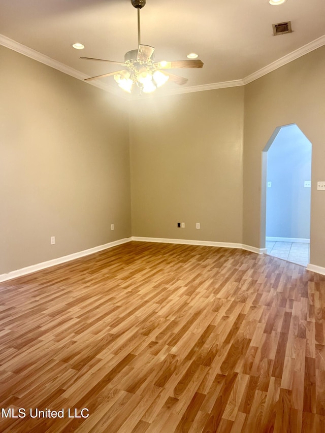 unfurnished room with light wood finished floors, a ceiling fan, ornamental molding, and arched walkways