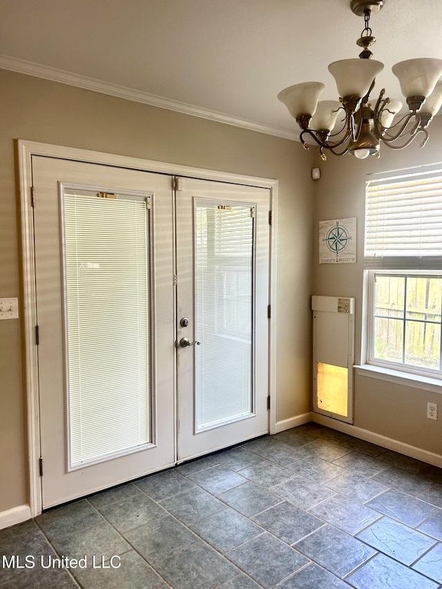 doorway featuring stone finish flooring, a chandelier, ornamental molding, and baseboards