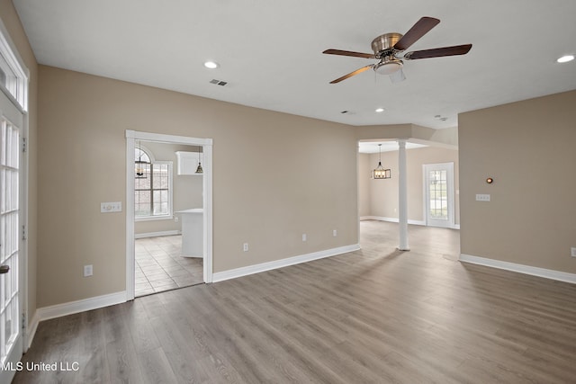 unfurnished room with ceiling fan, plenty of natural light, wood finished floors, and visible vents