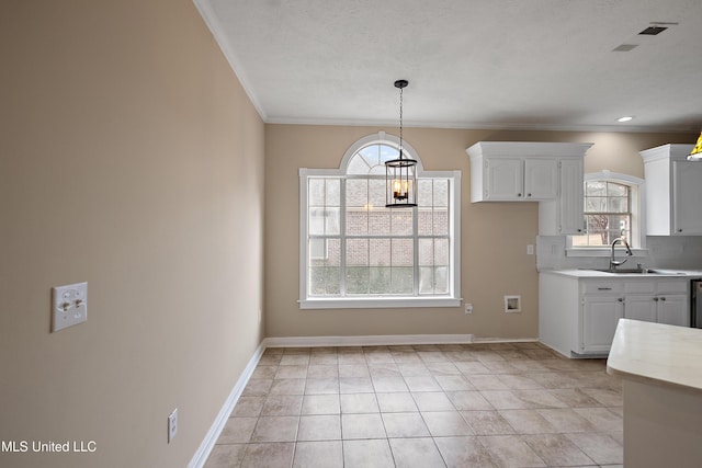 kitchen featuring a sink, baseboards, white cabinets, light countertops, and backsplash