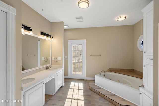 full bath featuring a sink, a jetted tub, baseboards, and double vanity