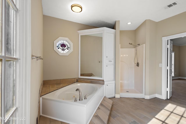 full bathroom featuring baseboards, visible vents, wood finished floors, a garden tub, and walk in shower