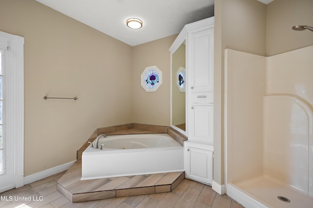 bathroom featuring a whirlpool tub, a stall shower, baseboards, and wood finished floors