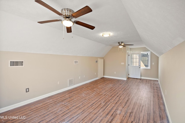 additional living space with lofted ceiling, visible vents, baseboards, and wood finished floors