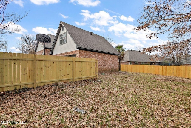 exterior space featuring brick siding, fence, and roof with shingles