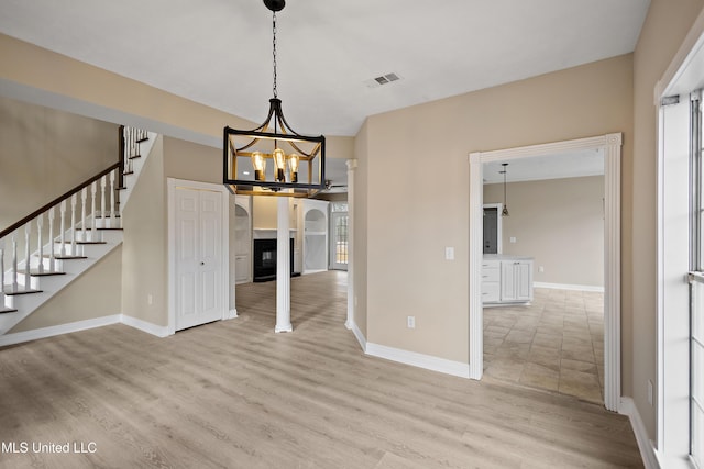 unfurnished dining area with a notable chandelier, visible vents, light wood-type flooring, baseboards, and stairs