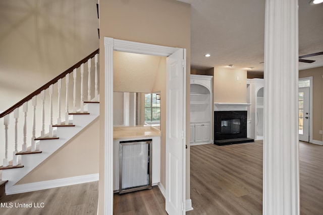 stairs featuring a glass covered fireplace, recessed lighting, wood finished floors, and baseboards