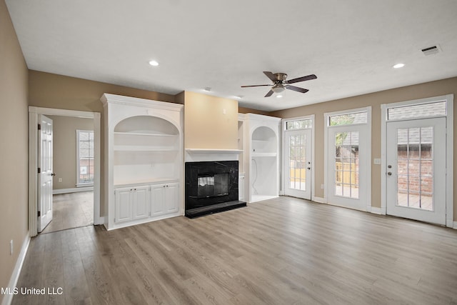 unfurnished living room with light wood-style flooring, a premium fireplace, visible vents, and recessed lighting