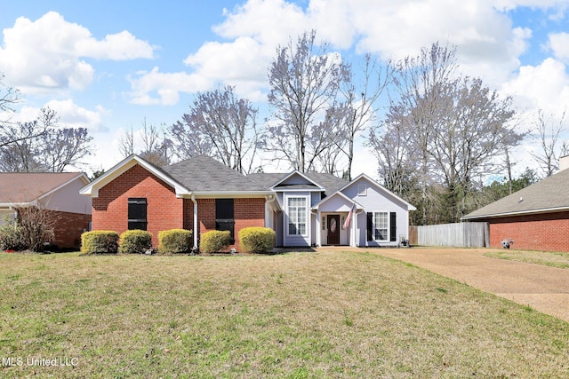 ranch-style house with a front lawn, fence, brick siding, and driveway