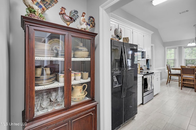 kitchen with visible vents, lofted ceiling, stainless steel appliances, hanging light fixtures, and white cabinetry