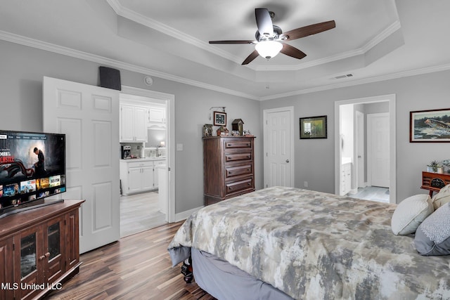 bedroom featuring a tray ceiling, light wood-style floors, and visible vents