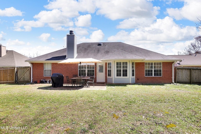 back of property featuring brick siding, a chimney, and a fenced backyard