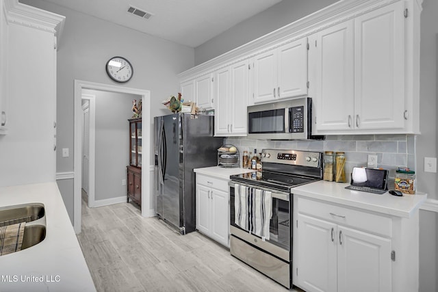 kitchen with white cabinetry, tasteful backsplash, visible vents, and appliances with stainless steel finishes