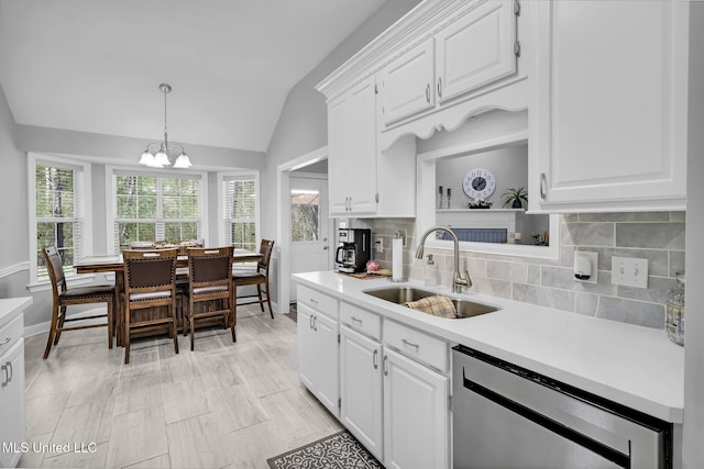 kitchen with a healthy amount of sunlight, dishwasher, light countertops, vaulted ceiling, and a sink