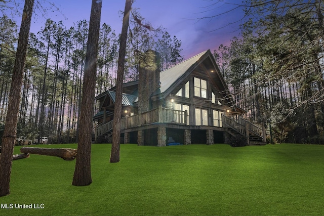 property exterior at dusk with a deck and a lawn