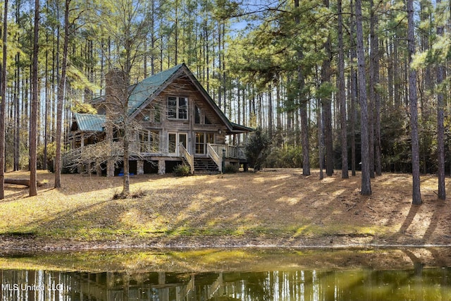 rear view of house featuring a deck with water view