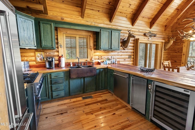 kitchen with wine cooler, appliances with stainless steel finishes, butcher block counters, and vaulted ceiling with beams