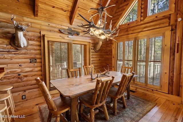 dining space with wood ceiling, wood-type flooring, plenty of natural light, a notable chandelier, and beam ceiling