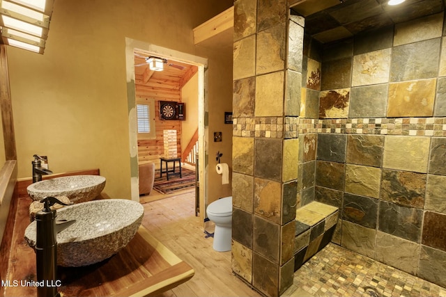 bathroom featuring a tile shower, sink, hardwood / wood-style floors, and toilet