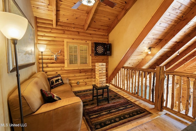 living area with lofted ceiling with beams, wood-type flooring, rustic walls, ceiling fan, and wood ceiling