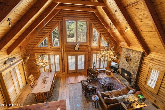 living room with wood ceiling, hardwood / wood-style flooring, an inviting chandelier, beam ceiling, and a fireplace