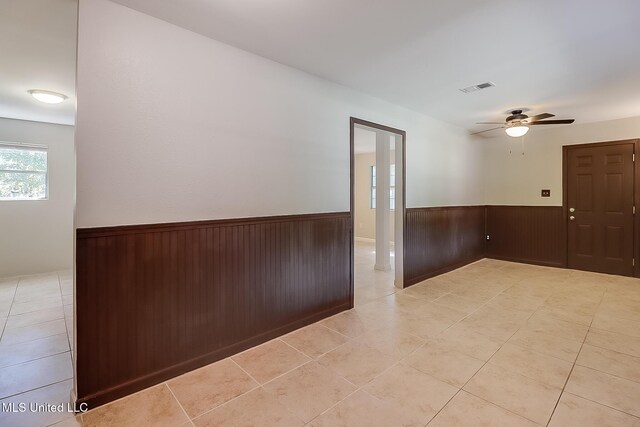 6533 Shawnee St, Kiln, MS 39556 - spare room with ceiling fan, visible vents, wood walls, a wainscoted wall, and light tile patterned flooring