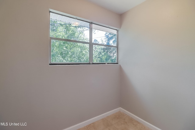 empty room with light tile patterned flooring and plenty of natural light