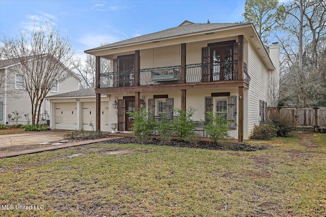 view of front of house featuring a balcony, a garage, and a front yard