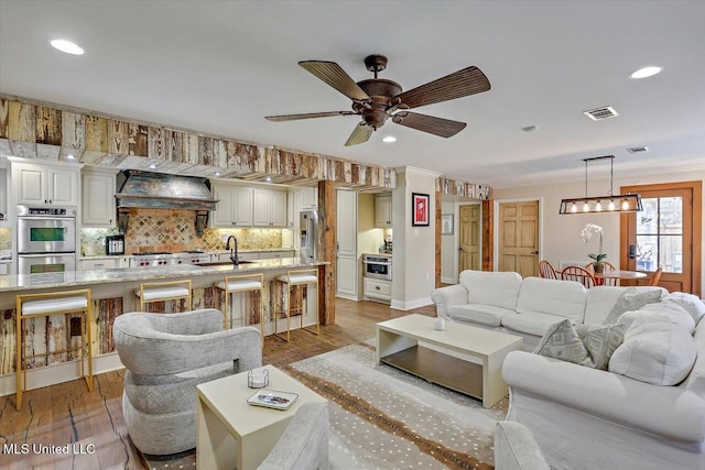 living room with sink, light hardwood / wood-style flooring, ornamental molding, and ceiling fan