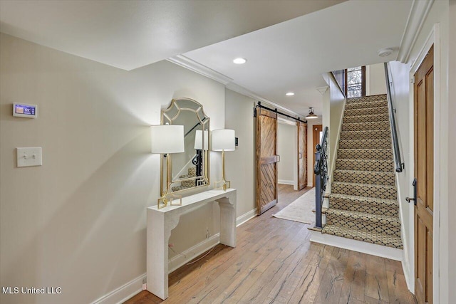 corridor with crown molding, a barn door, and light wood-type flooring