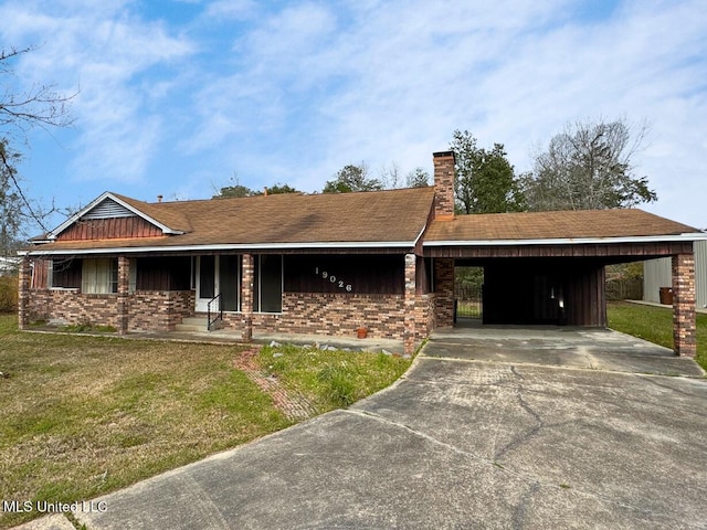 view of front of house with a front yard, concrete driveway, brick siding, and a chimney